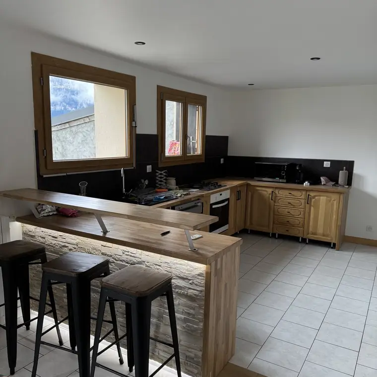 Cuisine en bois avec bar en pierre de parement et tabourets hauts