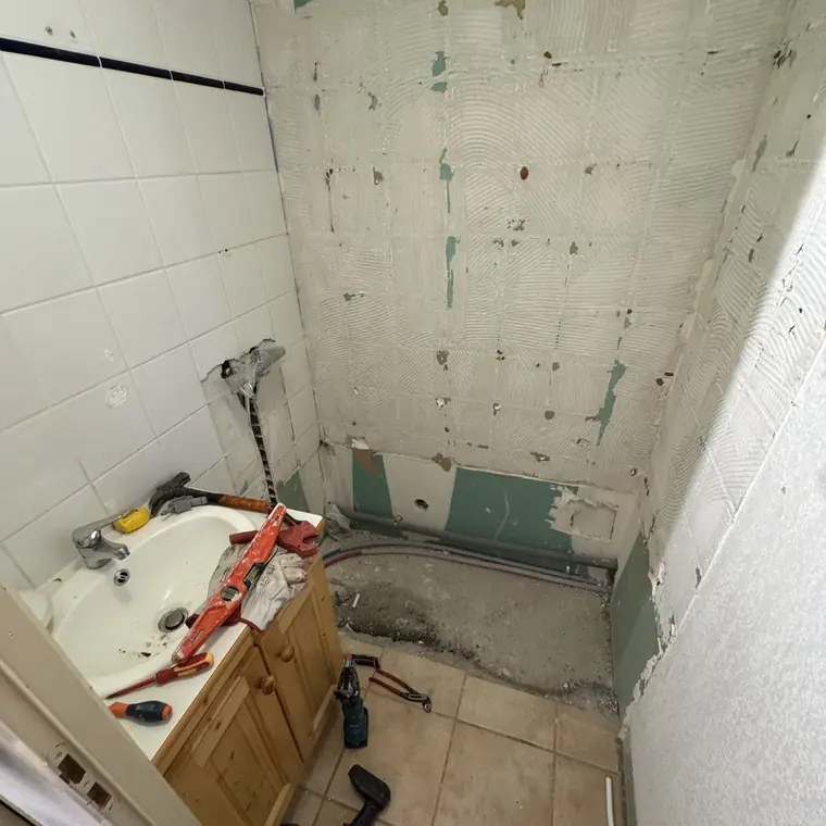 Baignoire en cours de dépose, murs piqués, outils au sol
