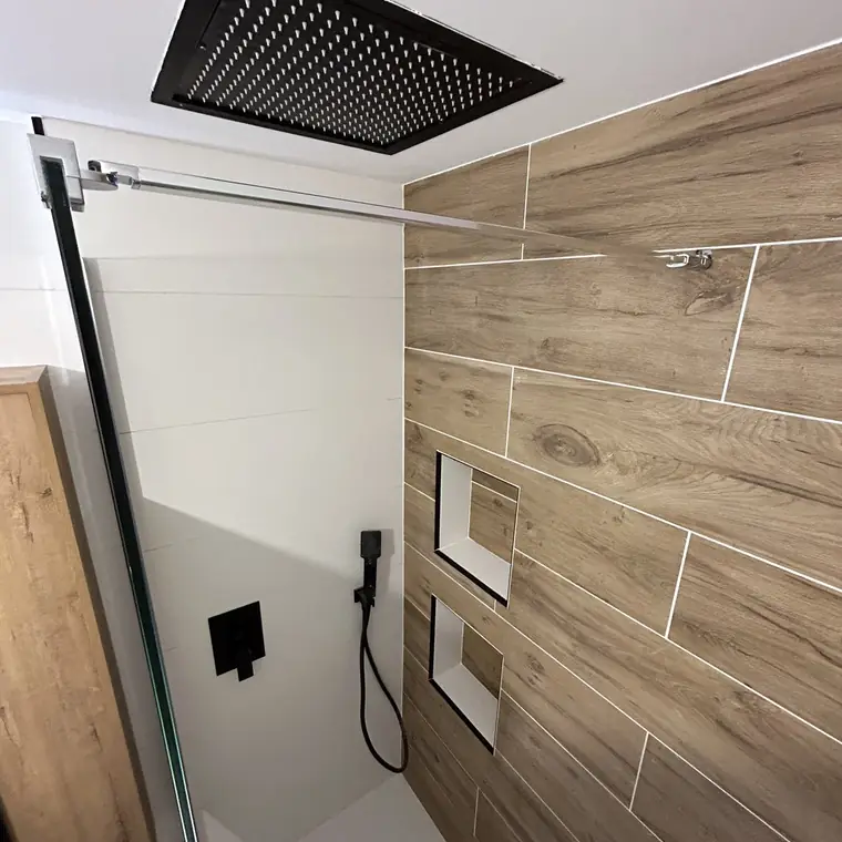 Douche avec carrelage imitation bois, deux niches et pomme de douche carrée au plafond