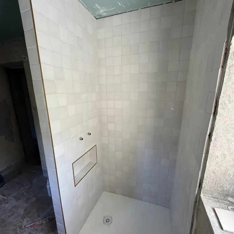 Douche carrelée en zellige blanc avec niche de rangement et receveur extra-plat
