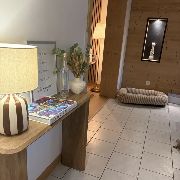 Entrée avec mur habillé de bois et niche éclairée au fond en marbre noir