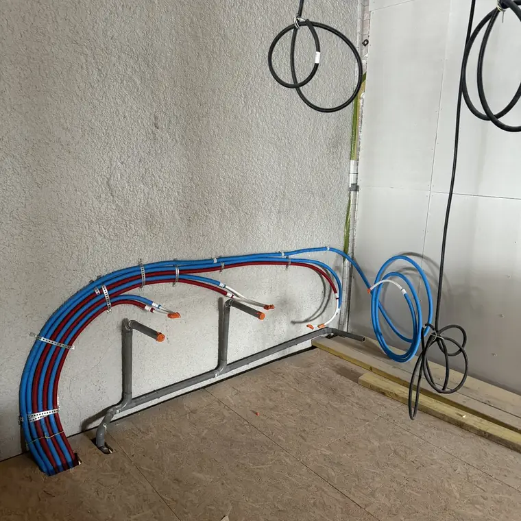 Alimentations en PER rouge et bleu fixées au mur, gaines électriques en attente