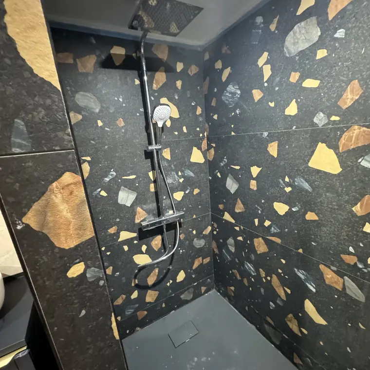 Douche entièrement carrelée en terrazzo noir à éclats clairs