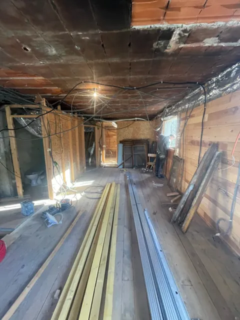 Pièce en chantier : ossature bois des cloisons, câbles au plafond, profilés métalliques au sol