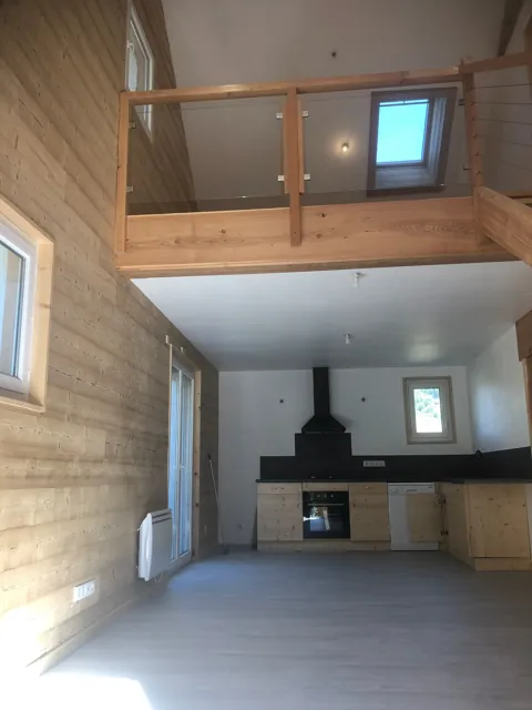 Pièce en double hauteur avec mezzanine en bois au-dessus d’une cuisine, murs en lambris