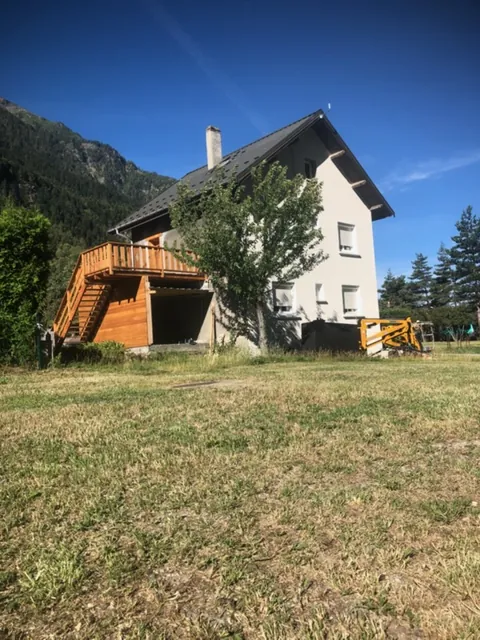 Maison en montagne avec une terrasse en bois sur le côté