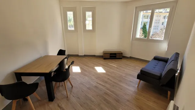 Séjour lumineux au sol imitation parquet, table en bois et canapé